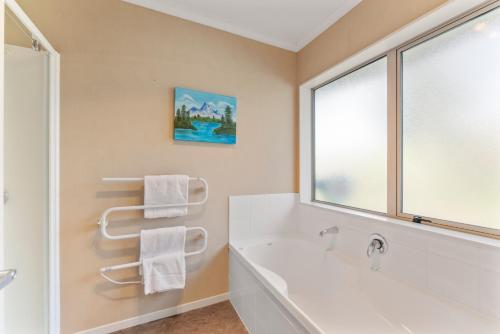 a bathroom with a tub and a sink and a window at Soak & Stay Acacia Bay - spa, pet, family friendly in Taupo