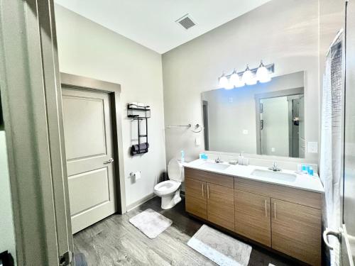 a bathroom with a sink and a toilet and a mirror at Uptown Charlotte Modern Stay 2BR in Charlotte