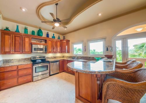 a kitchen with wooden cabinets and a center island at Belizean Cove Estates Beachfront Villas in San Pedro
