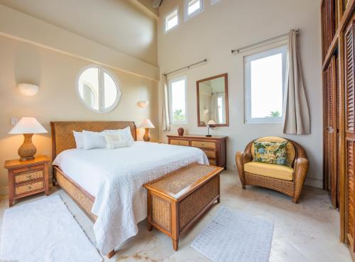 a bedroom with a bed and a chair and a mirror at Belizean Cove Estates Beachfront Villas in San Pedro