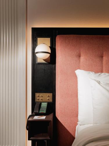 a hotel room with a bed and a table with a phone at Public House Bangkok, a Member of Design Hotels in Bangkok