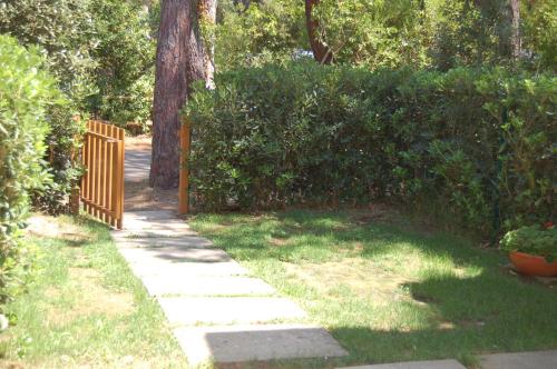 a garden with a wooden fence and a sidewalk at Girino II in Principina a Mare
