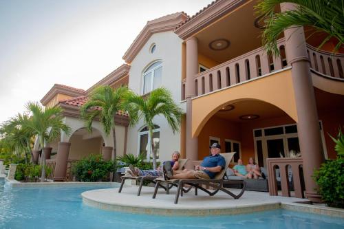 a group of people sitting on a bench in front of a house at Belizean Cove Estates Beachfront Villas in San Pedro