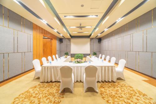 a conference room with a long table and white chairs at Bien Bac Hotel in Móng Cái