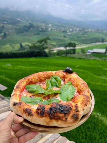 a person holding a pizza on a plate at Pavi garden in Sa Pa