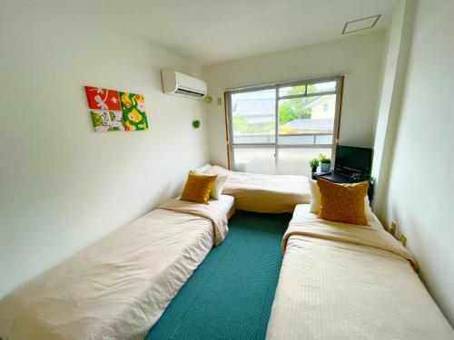 a room with two beds and a television in it at Sakura202 伊丹空港アクセス抜群タイニールーム最大3名宿泊可能 in Toyonaka