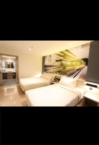 a bedroom with two beds and a painting of a train at Atour Light Harbin Central Street in Harbin