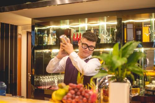 a man standing behind a bar holding a bottle at Bien Bac Hotel in Móng Cái
