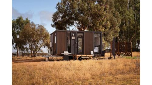 a tiny house sitting in the middle of a field at Kings Cottage by Tiny Away in Irymple