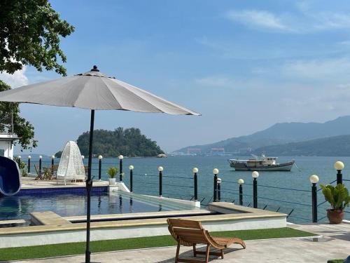 a pool with an umbrella and a boat in the water at Costa Del Subic in Subic