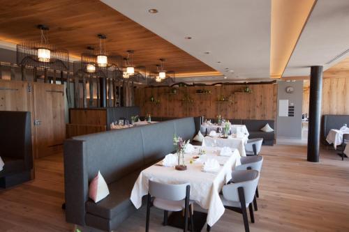 ein Restaurant mit weißen Tischen und Stühlen sowie Holzwänden in der Unterkunft Pension Örtlerhof in Dorf Tirol