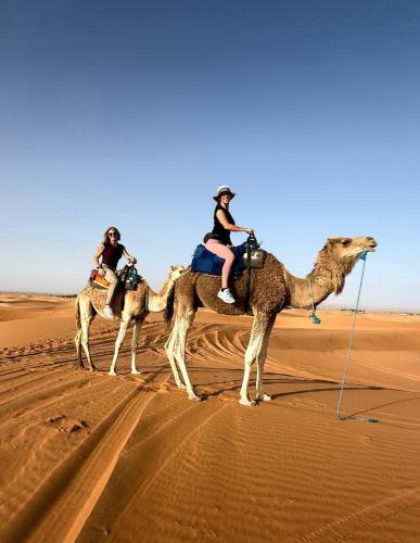 three people riding on the camel in the desert at Sahara Luxury Camp VIP in Merzouga