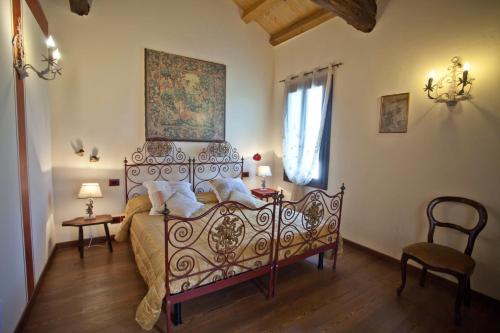 a bedroom with a bed and a chair and a window at Villa Verecondi Scortecci in Colle Umberto