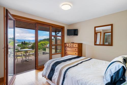 a bedroom with a bed and a balcony at Macpherson Street, Wanaka in Wanaka