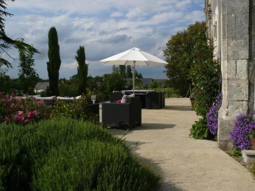 a patio with an umbrella and chairs and flowers at La Grouas in Vauchrétien