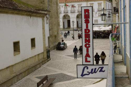 a sign for the entrance to a building with people walking down a street at Residencial Luz in Tomar
