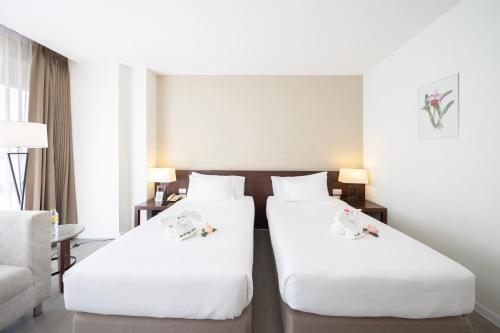 two beds in a hotel room with white sheets at Golden Crown Grand Hotel in Hat Yai