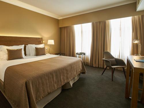 a hotel room with a bed and a desk and window at PortoBay Marquês in Lisbon
