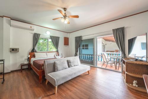 ein Schlafzimmer mit einem Bett und einem Stuhl und einem Balkon in der Unterkunft V205 Island Hideaway Near Promthep Sunset in Nai Harn Beach