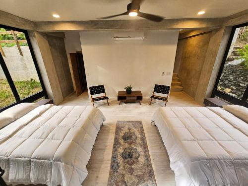 two beds in a room with large windows at Villa con piscina privada, West Bay Roatan in Coxen Hole