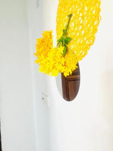a vase filled with yellow flowers hanging on a wall at Shikos Place in Watamu