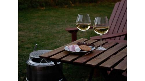 a picnic table with two glasses of white wine at Sugar Hut by Tiny Away in Great Horkesley