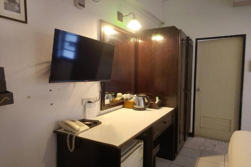 a kitchen with a desk with a television on the wall at Baan Orawee Boutique Hotel in Mae Rim