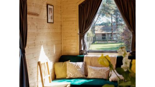 a living room with a green couch and a window at Vilasini Hut by Tiny Away in Great Horkesley