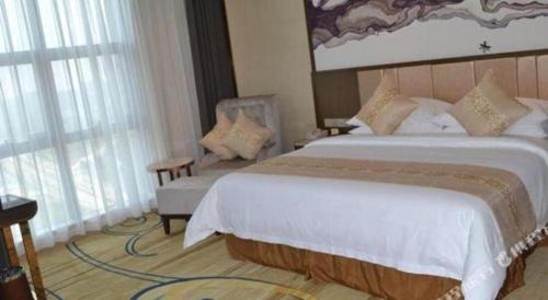a hotel room with a large bed and a chair at Venus Royal Hotel Nanning East High-Speed Railway Station in Nanning