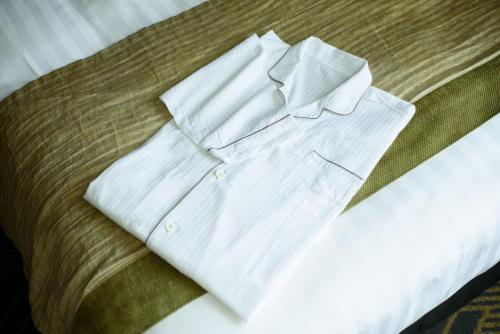 a white shirt sitting on top of a bed at Kanazawa Tokyu Hotel in Kanazawa