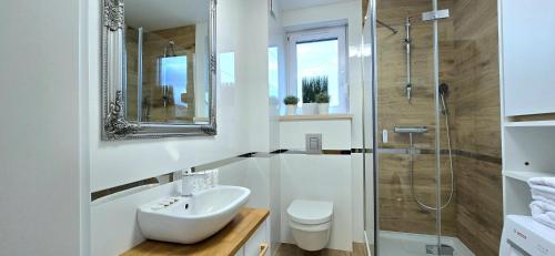 a white bathroom with a sink and a shower at TriApart Apartamenty Amber Beach Jantar in Jantar