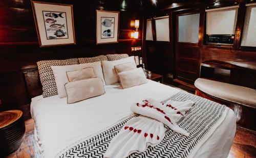 ein Schlafzimmer mit einem Bett mit weißen Laken und Kissen in der Unterkunft Behike Luxury Phinisi in Mantaak