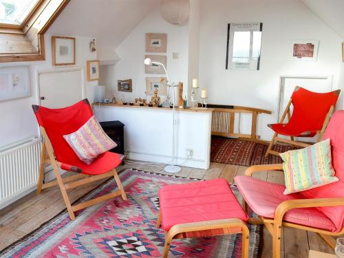 ein Wohnzimmer mit zwei roten Stühlen und einem Tisch in der Unterkunft Pollendor in Falmouth