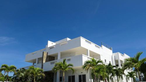 a white building with palm trees in front of it at Villa de 3 habitaciones frente al mar Roatán in Roatan