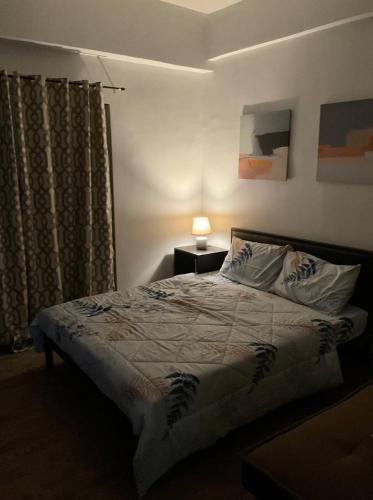 a bedroom with a bed and a lamp on a table at Cozy Staycation Near Cebu Airport with Pool & Gym , Free Wifi in Pusok