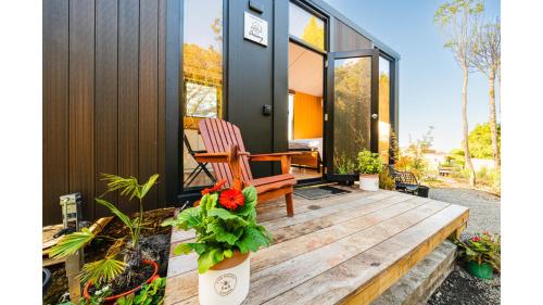 a house with a wooden deck with a chair on it at The Mini Mountain Hut 2 by Tiny Away in Egmont Village