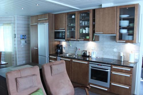 uma cozinha com armários castanhos e duas cadeiras em Rukan Mökit em Ruka