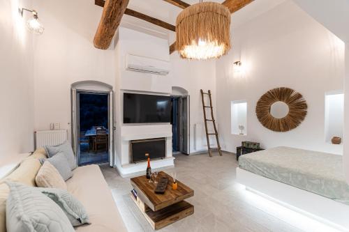 a white living room with a couch and a tv at Villa Melania in Mélanes