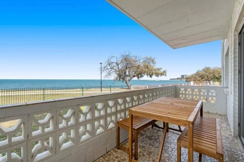 Una mesa en un balcón con vista a la playa. en Direct Ocean Front Apartment, en Redcliffe