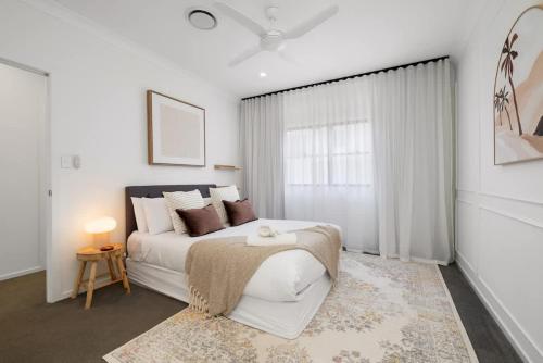 a white bedroom with a bed and a window at Inner City Townhouse in Brisbane
