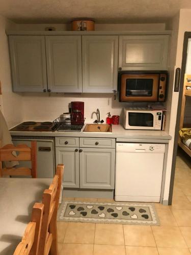 une cuisine avec des armoires blanches, un évier et un micro-ondes dans l'établissement STUDIO POINTE DES ARAVIS 4 PERS HTE-SAVOIE, à Saint-Gervais-les-Bains