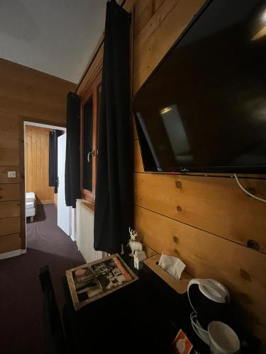 a room with a large tv on the wall at Hôtel Au Feu De Bois in Autrans