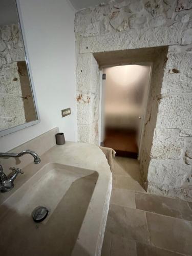a bathroom with a sink and a stone wall at Trulli Capomazza in Noci