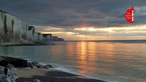 a sunset over the ocean with a beach and cliffs at Gite entre Mer et Vallée à Embreville in Embreville