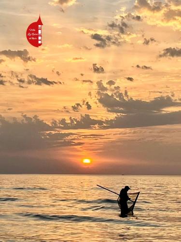 a man in a boat in the ocean at sunset at Gite entre Mer et Vallée à Embreville in Embreville