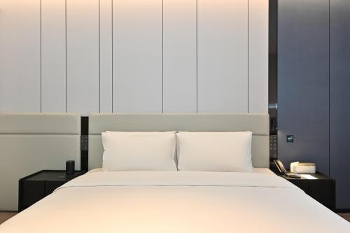 a bed with white sheets and pillows in a room at Atour Hotel Shenyang Taiyuan Street Democracy Square in Shenyang