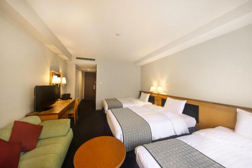 a hotel room with three beds and a couch at Hotel Nikko Nara in Nara