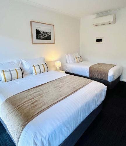 ブライトにあるAlpine Hotel Brightの白い壁のホテルルーム内のベッド2台