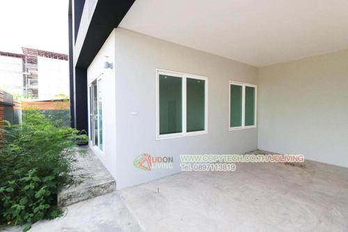 a white house with windows and a courtyard at Maximize Brand New Hostel Udonthani in Udon Thani