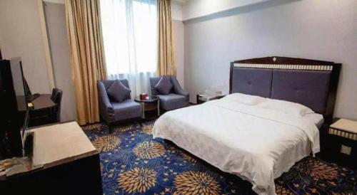 a hotel room with a bed and two chairs at Zhongshan Hui Quan Hotel in Zhongshan
